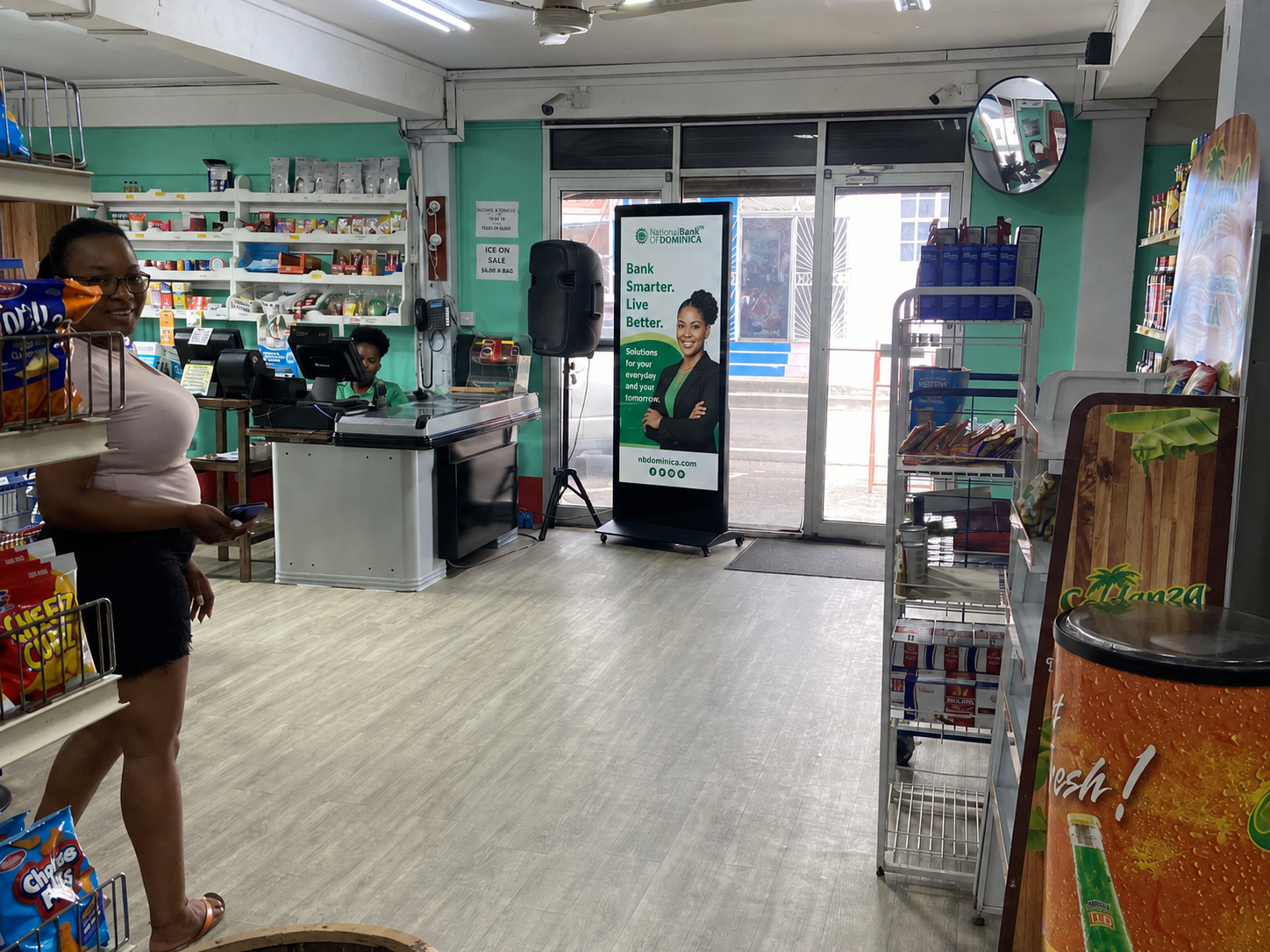 NBD campaign mockup on Reach Media screen in Roseau retail environment